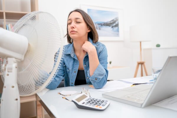 woman too hot in office using a fan